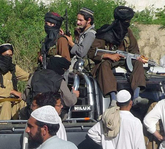 Pakistani Taliban fighters sit in the back of a truck with their weapons in Buner
