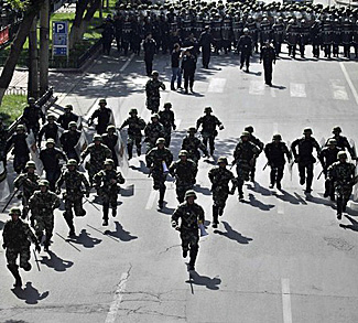 Chinese security forces chase off protesters during a demonstration at the centre of Urumqi