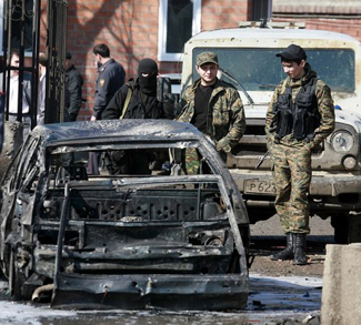 Interior Ministry servicemen stand next to a car that was blown up during a bombing in Karabulak
