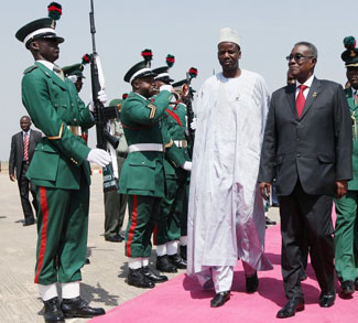 Ghana's President John Atta Mills inspects a guard of honour upon arrival for the ECOWAS meeting in Abuja