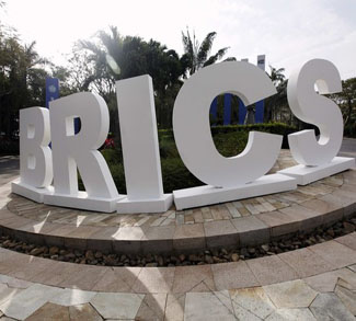 A man walks past a signage decoration for the BRICS summit outside Sheraton Hotel in Sanya