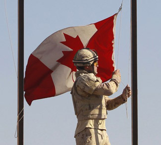 Canadian Army Private Drapeau lowers Canadian national flag during ceremony marking Canadian handover of forward fire base Zangabad to U.S. forces, in Panjwai district in Kandahar province