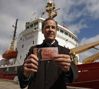 Bank of Canada Governor Mark Carney holds the new Canadian 50 dollar bill, made of polymer, in front of the CCGS Amundsen, the Arctic research vessel depicted on the back of the new bill, in Quebec City