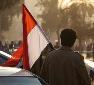 A human rights protestor in Egypt carries an Egyptian flag.
