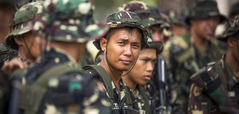 Philippine Army Pfc. Alex Jatass, center, waits to start helicopter insert and extract training with U.S. soldiers on Fort Magsaysay, Philippines, April 29, 2014. U.S. Marine Corps photo by Staff Sgt. Pete Thibodeau , modified, public domain