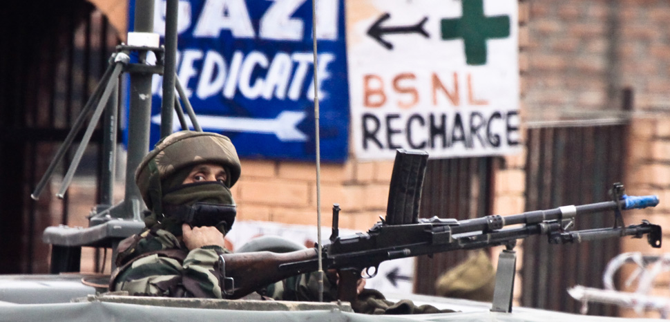 A soldier guards the roadside checkpoint outside of Srinagar International Airport (SXR) in Jammu and Kashmir, India., cc Jrapczak, modified, https://commons.wikimedia.org/wiki/File:Keeping_Watch.jpg